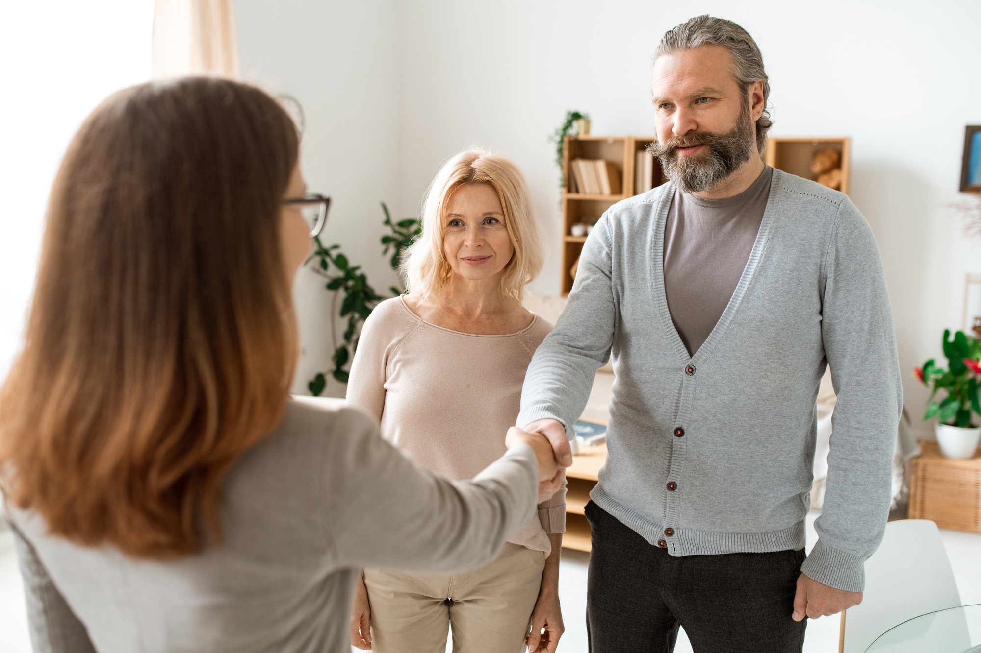 Mature casual couple greeting their real estate advisor in office